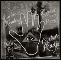 A store window with Psychic Reading sign and a large hand symbol with a third eye in the center.