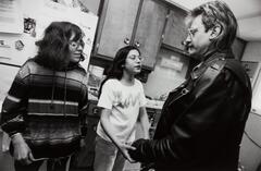Three people in a kitchen, the man and girl are holding hands.