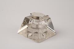 Inkwell made with clear crystal and glass has a shape of inclined pyramid body and a flat top. There are cut crystal inside the inkwell as decoration.