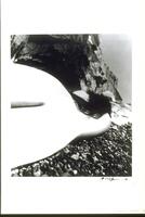 A photograph of a nude woman on the rocky East Sussex coast. The perspective of the image creates a strange elongation, abstracting the female form.