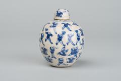 Miniature rounded jar with cover, decorated with blue figures of boy acrobats.