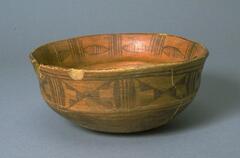 Shallow brown bowl with uneven rim, brown slip design on the outside and inside. 