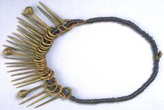 Belt with blue glass beads and brass pendants. Three pendants are in the form of crotal bells while the rest are in the form of spikes. 