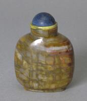 A square (corners are curved) quartz snuff bottle. On top of it is a mouthpiece with a blue stopper.