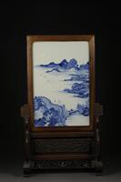 Blue and white porcelain screen, showing mountains, bridge with travelers, trees, mounted into rosewood frame decorated with blossoming lotus vines and scrolled ends probably made in the late 19th century.