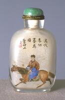 Rock crystal snuff bottle with man on horse and Chinese text. On the top is a brass collar and green jadeite stopper.
