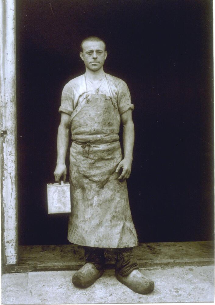 A formal portrait of a man standing in the doorway of his studio. 