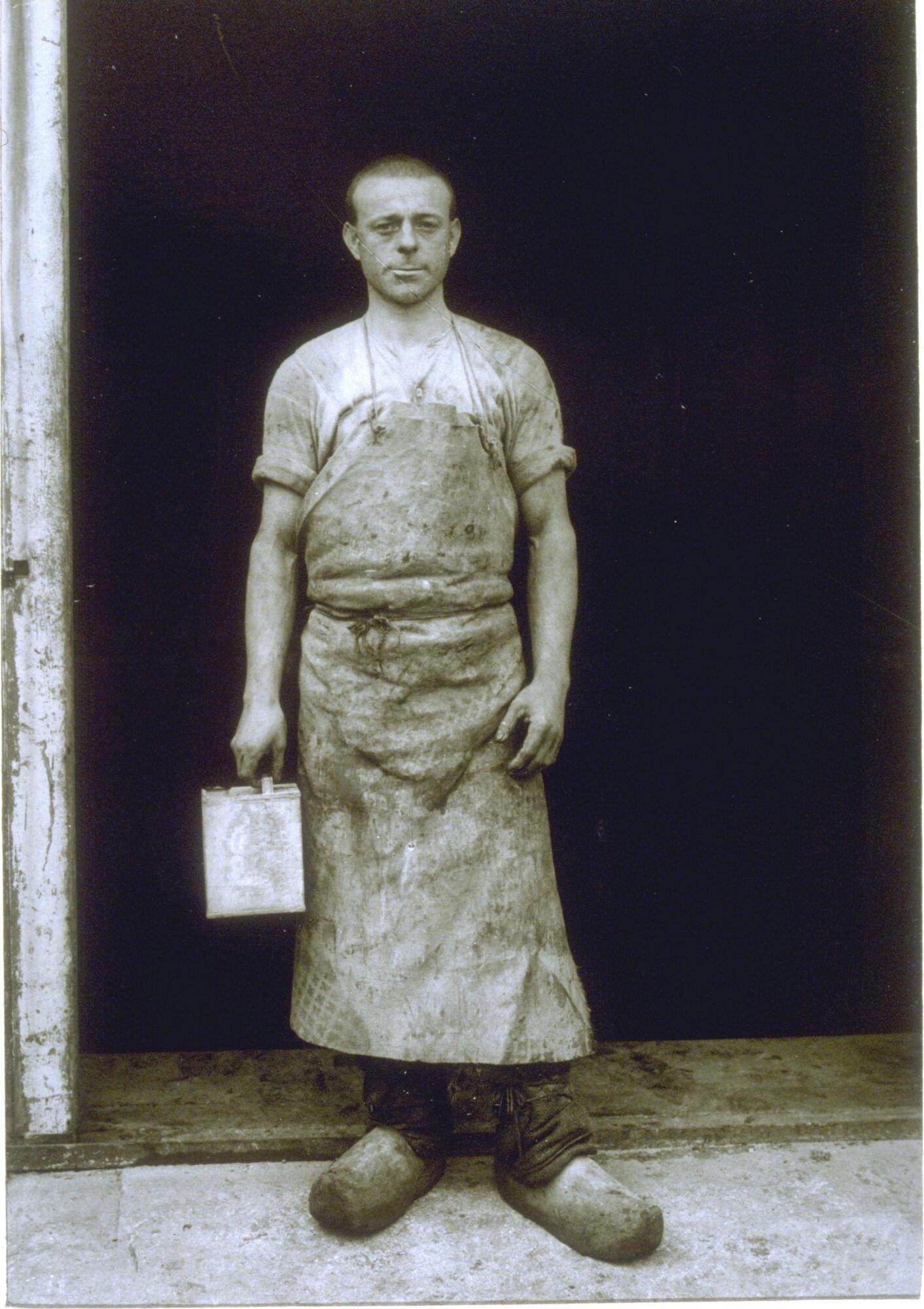 A formal portrait of a man standing in the doorway of his studio. 
