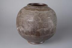A round, sphere-shaped vase. Brown-ish matte ash glaze with brushed arch patterns in small waves going around entire object.