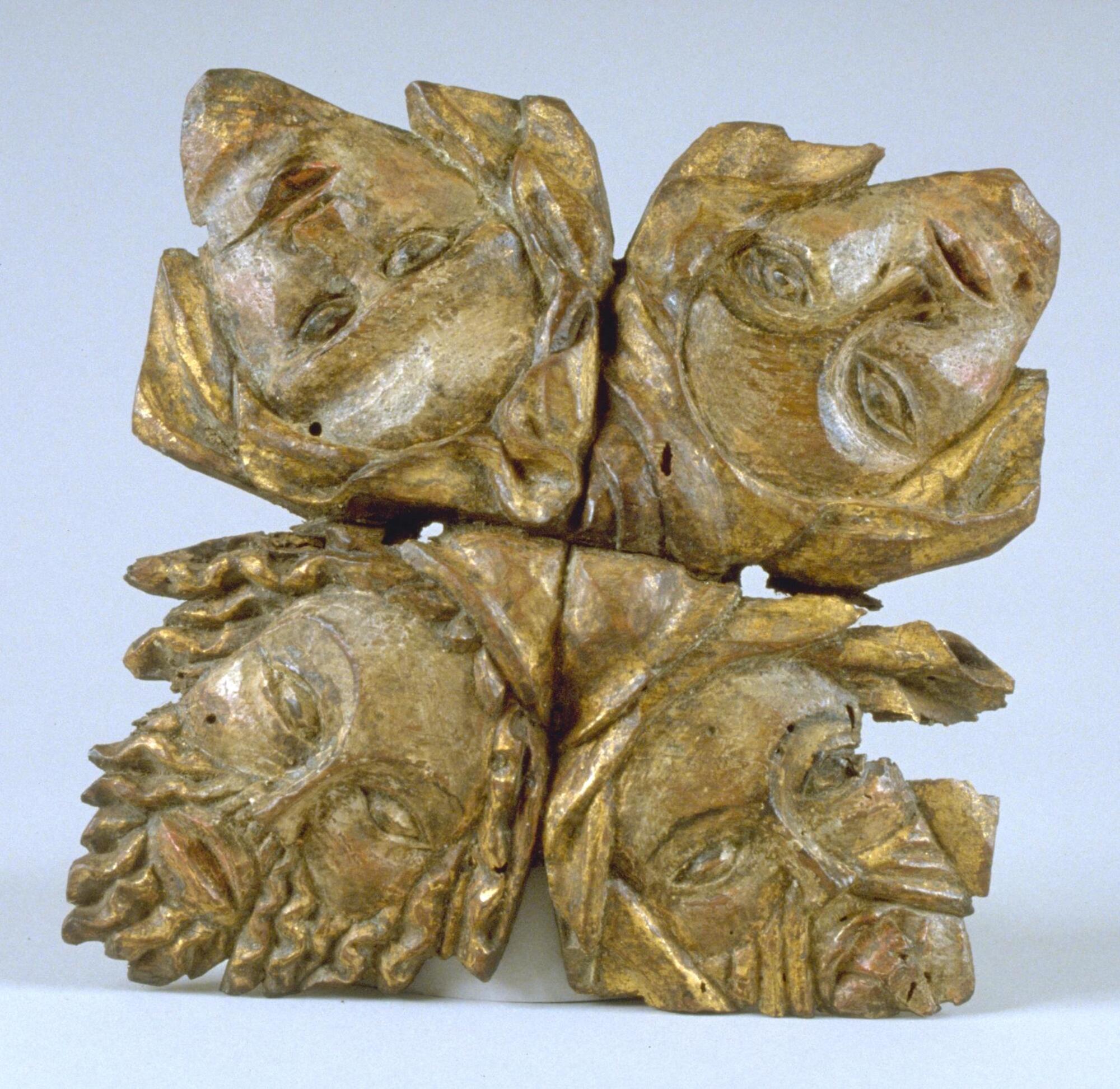 This ceiling boss features four faces with traces of paint that are arranged in a radial pattern with the crowns of their heads converging on a single, central point. Two of the faces are female, identifiable by the wimples worn on their heads, while the other two, wearing small pointed caps and sporting beards, are male. The symmetrical regularity of the piece is counterbalanced by subtle asymmetries introduced by differences in detail and the sequence of facial types.