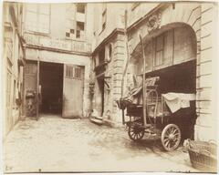 Interior courtyard with a large wagon parked in a doorway.