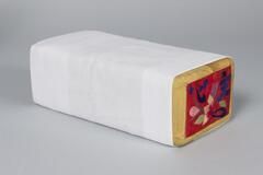 Wood rectangular pillow covered in a white cotton slip with embroidered flowers on the end. Red base with gold border containing blue Korean characters.