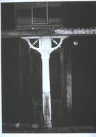 Photograph of a white painted post holding up the tin roof of a porch.