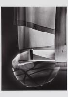 Play of light and shadows on a curtained window, window sill, and interior wall.