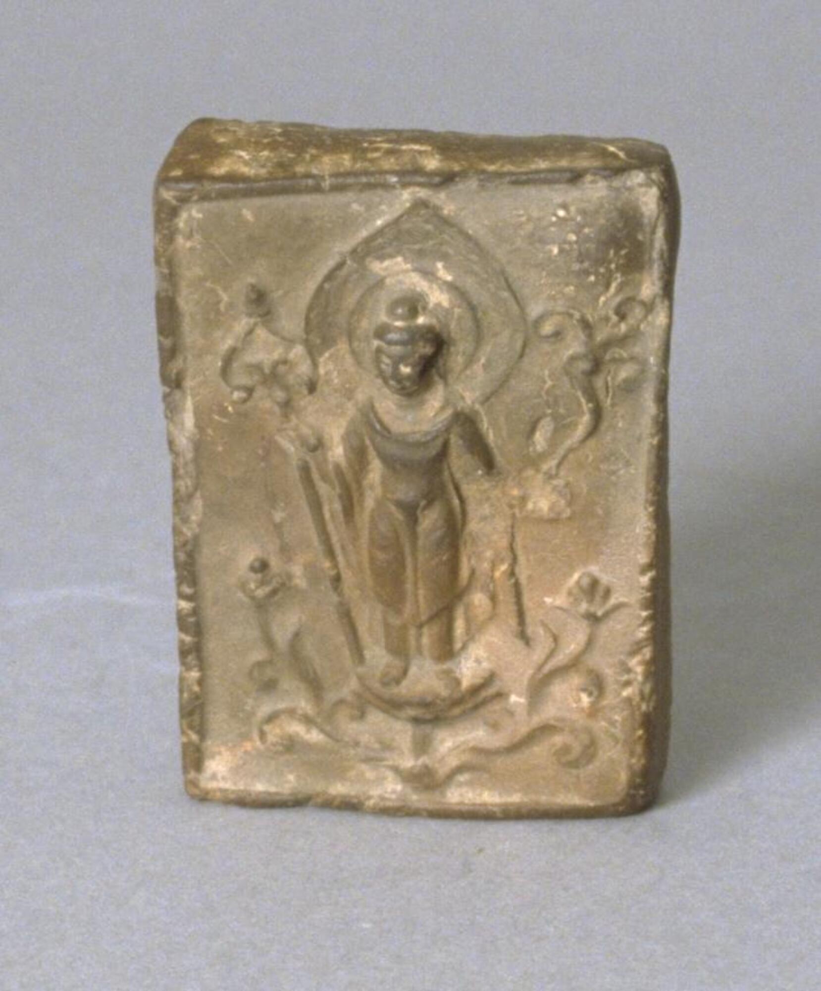 A small, thin, molded clay plaque with a bas-relief scene.