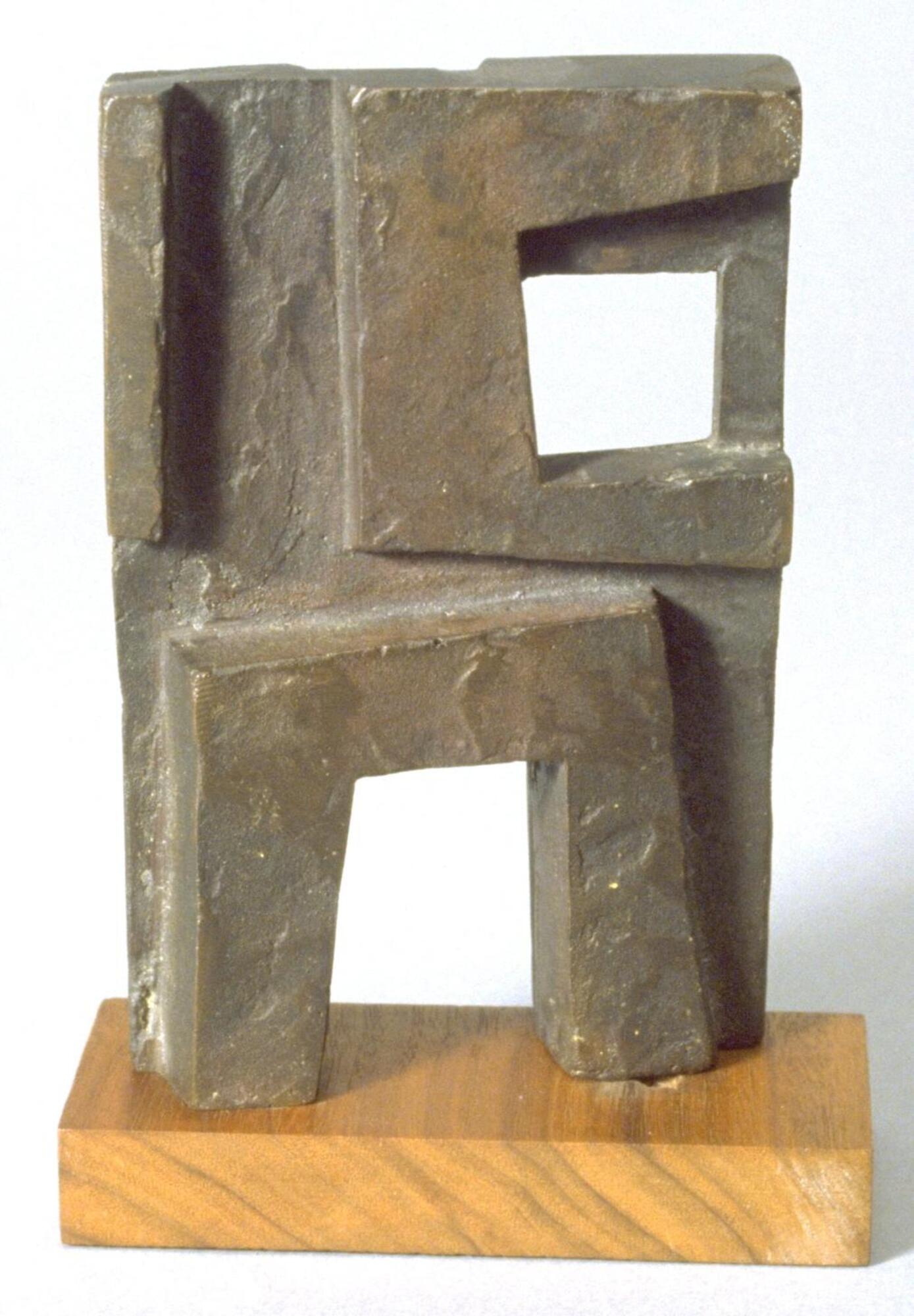 Thin, double-side, H-shaped bronze sculpture. Each side is made up of a collection of rough rectangle shapes overlapping and butting up against one another. Two rectangle-shaped openings penetrate the piece.