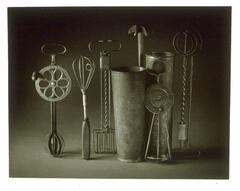 A photograph of a group of utilitarian objects arranged for a still life. The metal objects are various kitchen utensils.