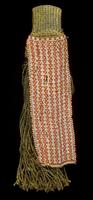 Apron in the form of fiber fringe attached to a woven loop at the top. Over the fiber is rectangular red and white beadwork with a pattern of triangles and small dots. 