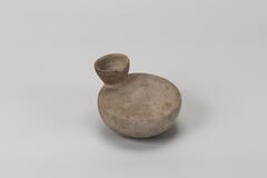 It is a urinal earthware. There is a everted mouth on the round body. It is unglazed.<br />
<br />
This is a gray, turtle-shaped, low-fired earthenware bottle. The neck is attached to one end of the body, rising outwards before flaring out once again. Its rim is round. The inner surface of the neck and the lower part of the body show signs of rotation and water smoothing. The bottom of the bottle is rounded.
<p>[Korean Collection, University of Michigan Museum of Art (2017) p. 77]</p>
