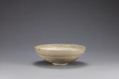 It has a relatively wide mouth for its height and slightly surving sides. The glaze was degraded. It was incised with arabesque design and inlaid with white slip.<br />
&nbsp;
<p>This is an inlaid buncheong bowl which is thought to have been excavated from a pit grave of early Joseon period. The inner base is inlaid with two concentric circles encircled by a yeoui-head band, and the inner wall is decorated with baoxianghua scrolls. In the middle of the outer wall is inlaid with three to four horizontal lines. The glaze was peeled off in parts, exposing the clay body, and there are traces of glaze running.</p>
[Korean Collection, University of Michigan Museum of Art (2014) p.145]