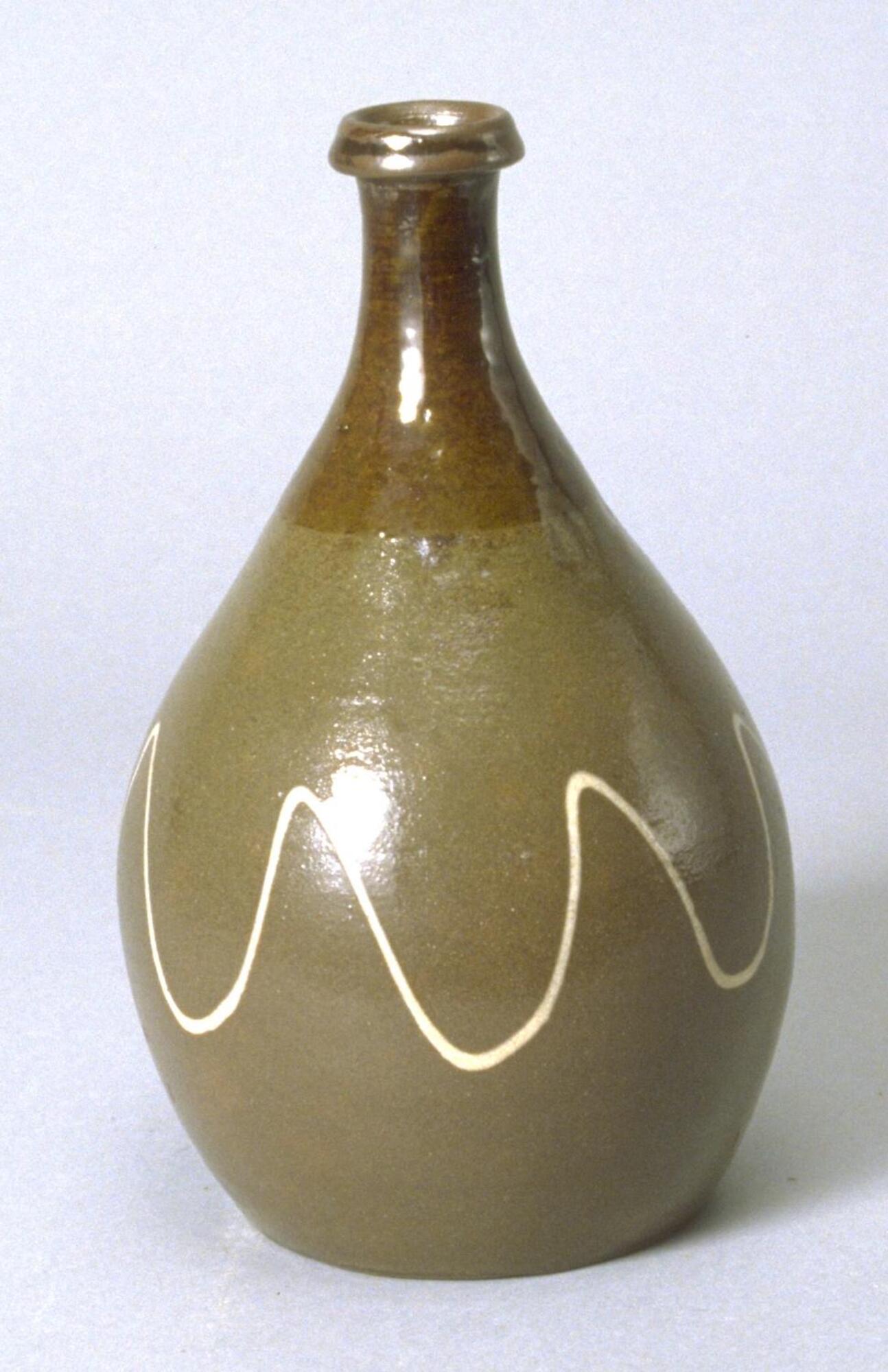 Bottle with full, rounded base that tapers into a thin neck that terminates in a lipped rim.  From the neck up, the vase has a brown glaze.  The body has a brownish gray glaze with a white drizzled squiggle decoration along it.