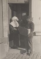 A nun and postman exchanging a signature for a package.