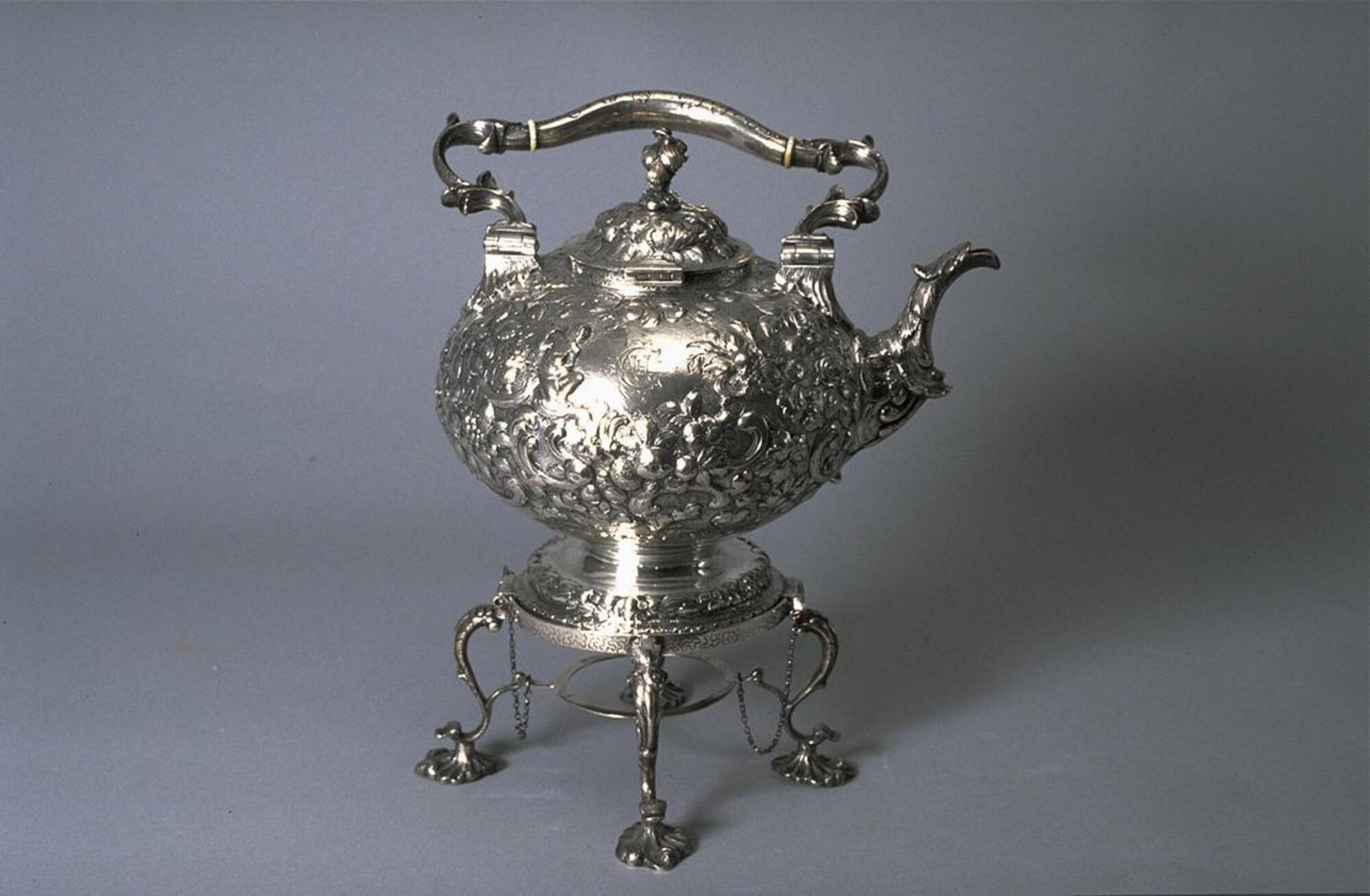 Silver teakettle and stand with hinged handle and opulent repouss&eacute; decoration