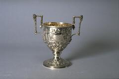 Two-handled cup with stemmed foot, square handles and opulent repouss&eacute; decoration