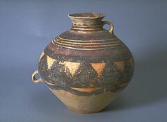 A light reddish-buff earthenware <em>guan (</em>罐) jar with wide globular upper body and conical lower body on a narrow flat base, and a tall narrow neck with flaring rim. There are two diametrically opposed lug handles, one at the waist and the other joining the neck to the shoulder. The upper half of the body is painted with black and red pigments to depict alternating sets of three thin black bands, and thick red and black bands. Below these bands is a wide black, fringed zigzag band and a lobed black band. Thin black bands around the neck, with a red band and black hatchmark band to the interior rim. There is loss and restoration to the rim.