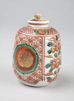 White ceramic jar with red hatching, green, black and gold painted designs. Has a small opening on top with a rounded edge. This is a part of a portable tea set.