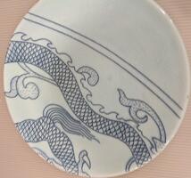 A plate from the border of the piece. Two blue lines cross from the upper left to the lower right. Below the lines are a portion of the dragon&#39;s scaly body.&nbsp;