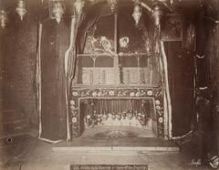 Frontal view of an altar space surrounded by draped fabrics with different patterns and materials. A staircase ascends out of the frame on the left-hand side of the image.
