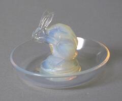 Clear glass saucer with milky, iridescent free-standing form in the center shaped like a rabbit.