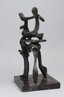 This is a bronze sculpture that has a series of abstract forms weaving together on a dark stone base.