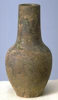 This long-necked bottle has a matte glaze of tans, brown, and orange. It also has a raised pattern that at first looks like a craquelure pattern.