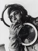Close-up view of a man in a test-pilot's suit smoking a cigarette.