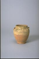 A thickly potted stoneware jar with wide globular shoulders tapering to a base on a footring.  It has a wide, straight short neck with a direct rim, and four loop lugs around the junction of where the neck meets the shoulder.  The upper third and interior are covered in an amber-green glaze. 