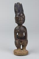 Standing male figure on a round base with hands at the sides. There are five strands of beads around the waist, four black and one red. Along the center front there is a long, deep groove. On each cheek there are incised, horizontal marks and the hair is in the shape of four tall lobes with two smaller lobes in the front. The hair is decorated with vertical grooves and coated in blue pigment. 