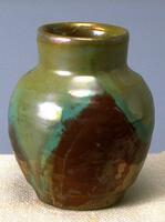 This vase has a high neck and gently sloping shoulders; an iridescent glaze glaze of greens and tan overlays a deep brick red on the main body of the vessel.