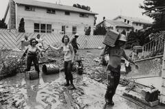 A group of people standing in the middle of a flooded area looking through their belongings.