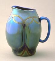This small blown glass pitcher consists of bands of glass applied to the body of the vessel; as the pitcher was blown, the glass between the bands expanded, shaping the vessel into four lobes.