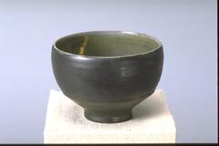 Footed bowl-shaped vessel with iridescent dark gray-black glaze