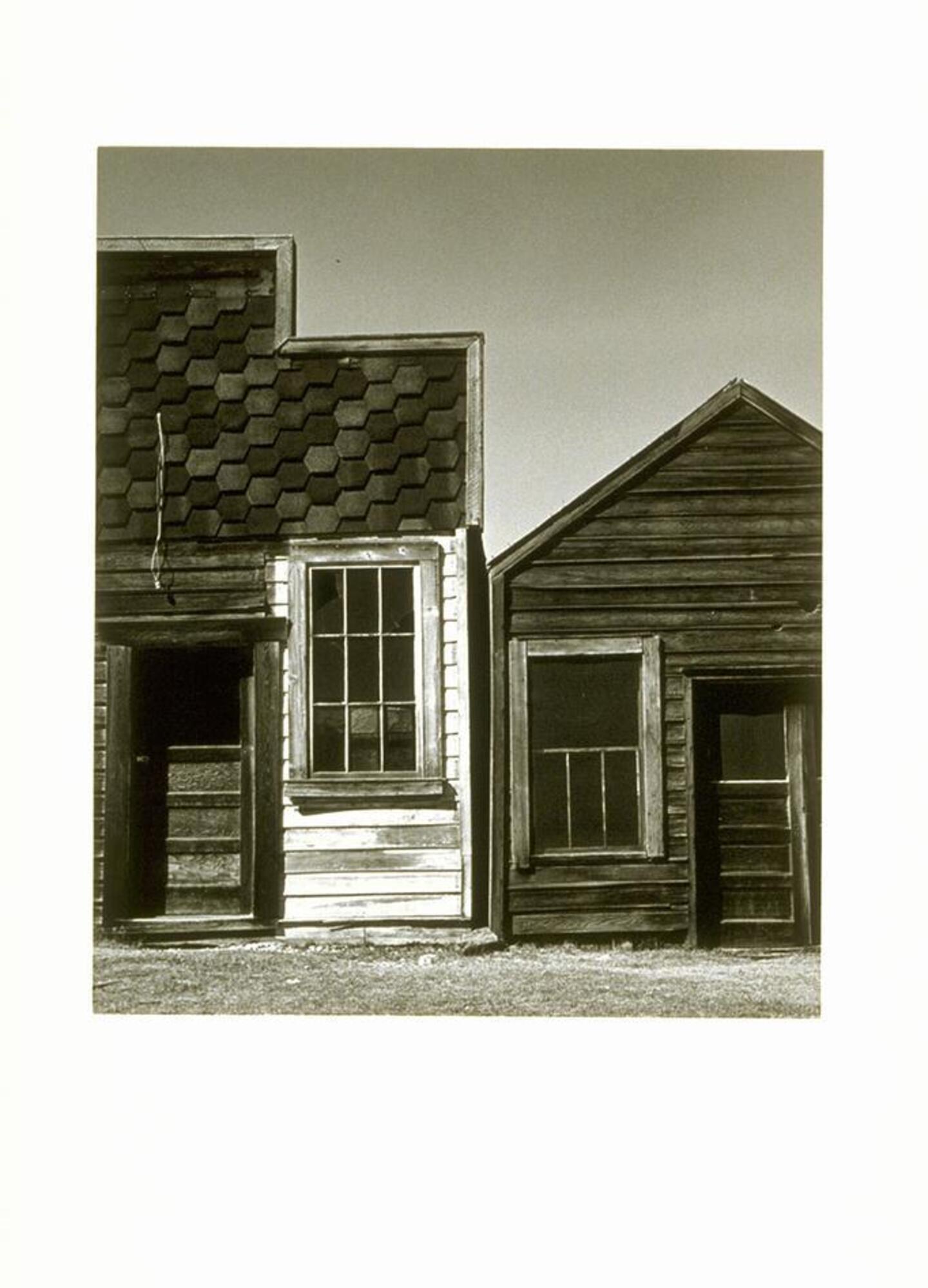 Photograph of the fa&ccedil;ades of two wooden buildings.