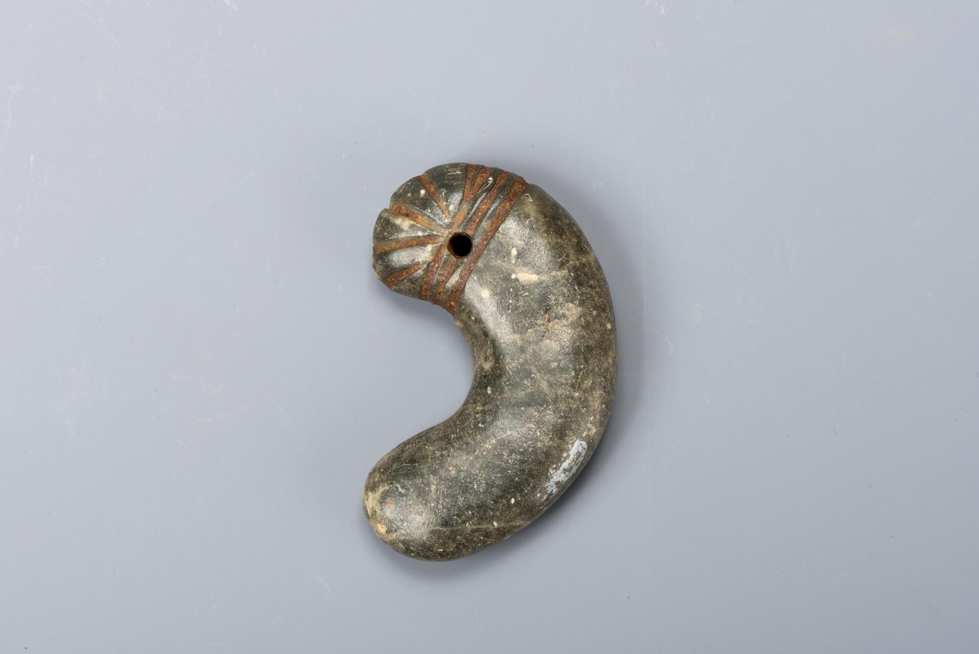 It looks like a rescent, animal&#39;s tooth or fetus. There is a hole and some carved line on the head part.<br />
<br />
This is a comma-shaped bead made from dark green jade. Such crescent moon-shaped beads, referred to as<em> gogok</em>, were used to decorate golden crowns, clothing, and belts. This example, which was attached to other ornaments via the hole in its head, is typical of comma-shaped beads of the Three Kingdoms period. Three parallel lines are incised across the hole, from which four more incised lines radiate upwards.<br />
[Korean Collection, University of Michigan Museum of Art (2017) p.33]
