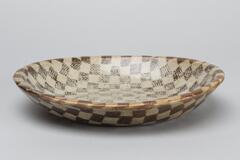 Oval bowl with a gray and brown checkerboard design overlayed with a feathered pattern.