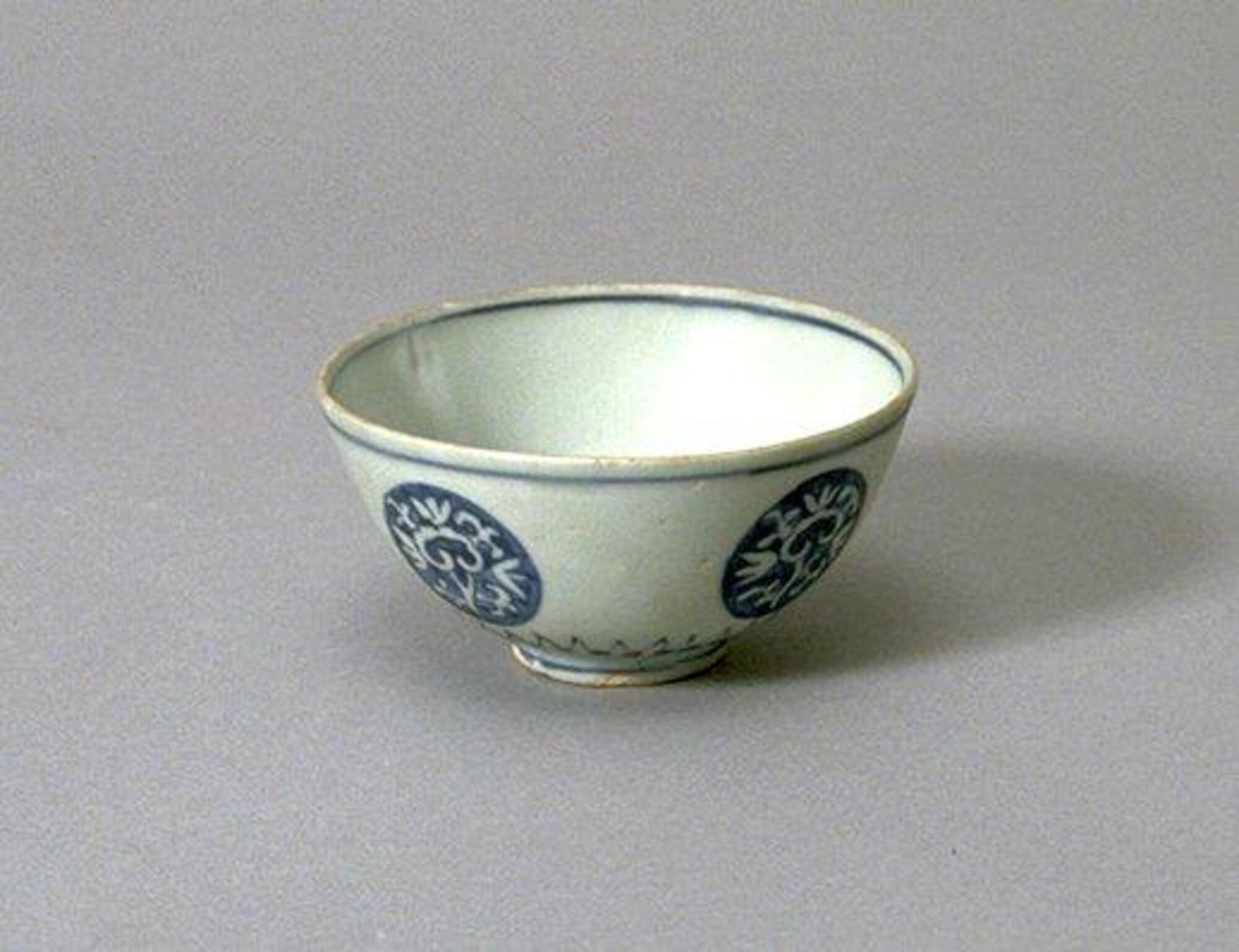 Blue and white porcelain bowl with medallion designs and blue line surrounding the rim.