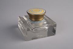 A crystal inkwell with a rectangular shape body and a yellow lid.