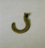 Flat piece of brass in the shape of a hook with round, flat end and a raised braided pattern.