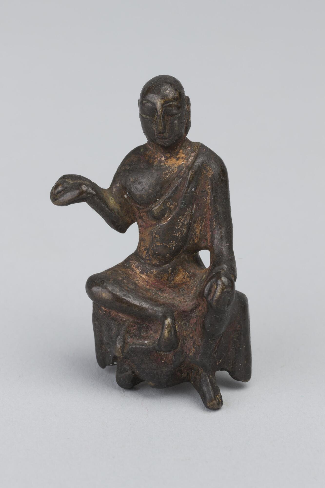 Seated figure with its right arm bent at the elbow and palm facing upward.