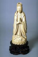Guanyin is wearing a robe and is sitting with her legs crossed and hands in Anjali Mudra.&nbsp;